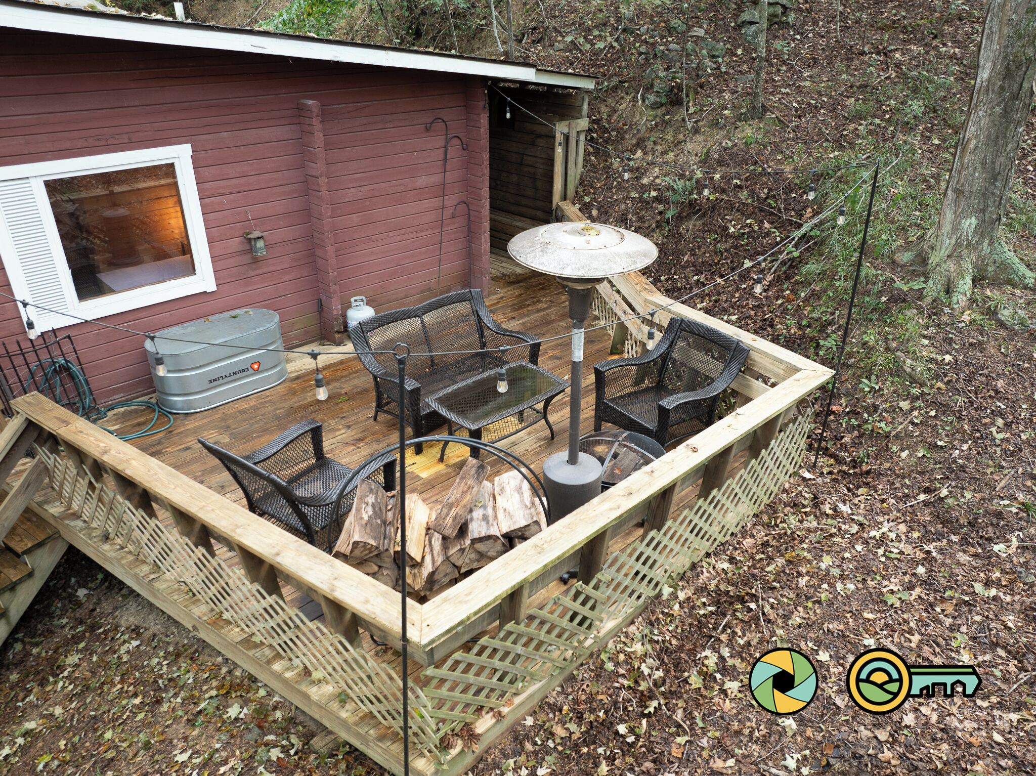 A wooden deck with outdoor furniture, a gas cylinder, and a small shed.