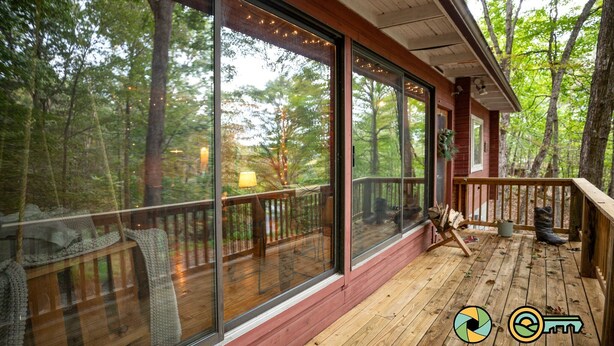A wooden deck with large windows overlooking a forest. - Basye Retreat - Authentic log cabin coziness! (Mount Jackson)