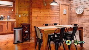A wooden interior with a dining table, chairs, a clock, and a deer head mounted on the wall. - Basye Retreat - Authentic log cabin coziness! (Mount Jackson)