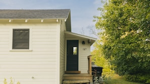 A single-story house with a front door marked "127" and a small porch. - Peaceful Cottage on Maine Flower Farm (Buxton)