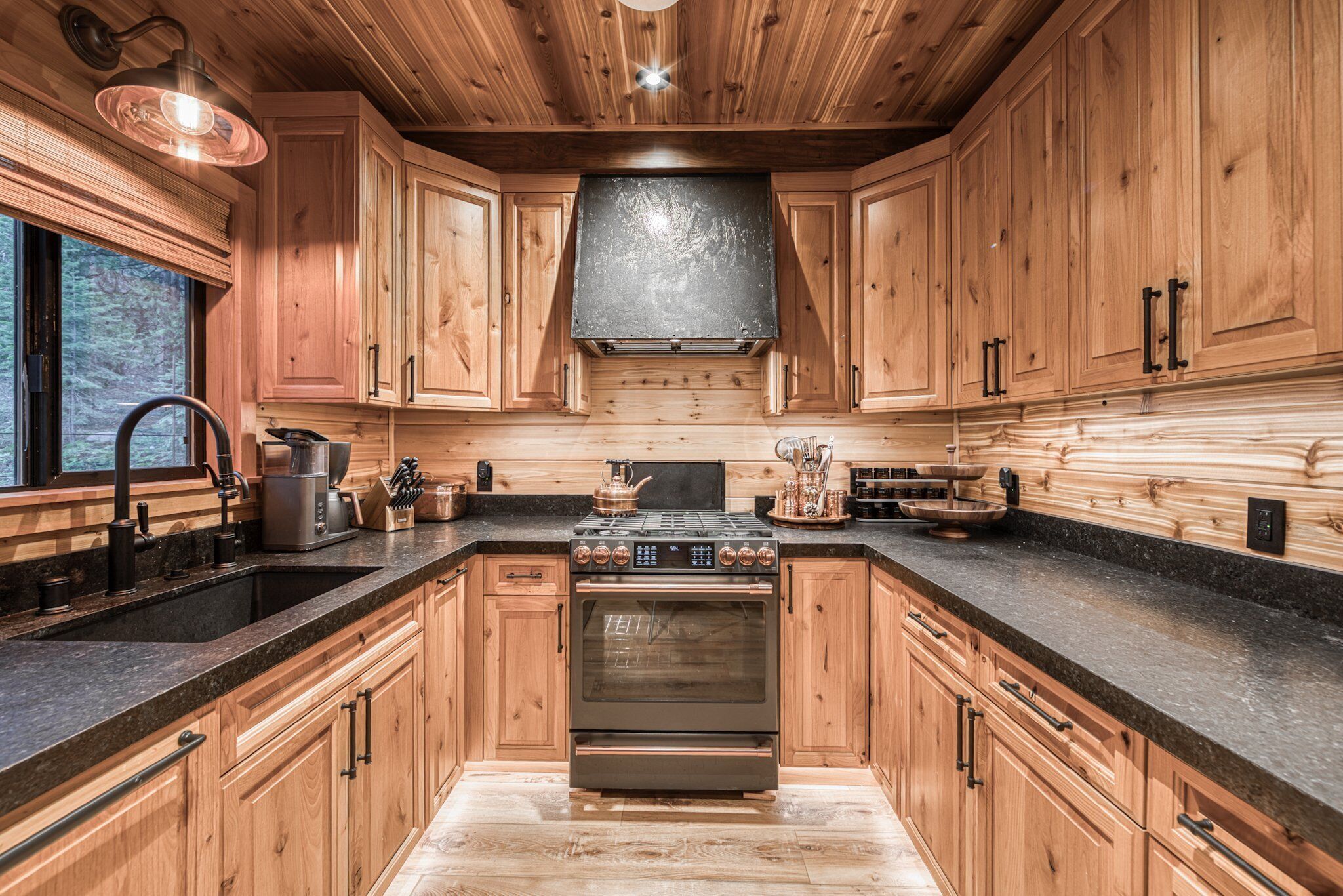A kitchen with wooden cabinets, a stainless steel stove, and a black countertop.