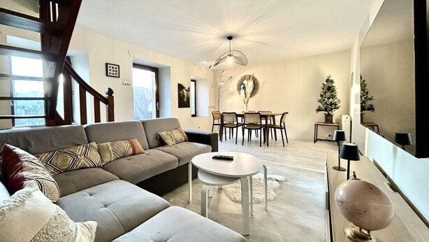 A modern living room with a sofa, a round table, and a dining area with chairs. - LE MAGNOLIA - LES MOLLETTES (LES MOLLETTES)