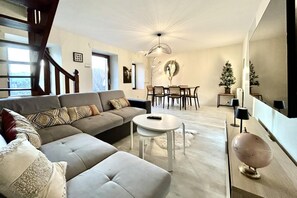Ein modernes Wohnzimmer mit einer Couch, einem runden Tisch und einem Essbereich mit Stühlen.
