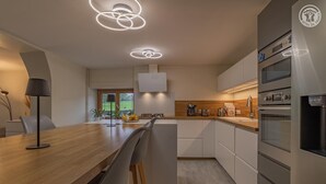 A modern kitchen with a wooden countertop, stainless steel appliances, and pendant lighting. - LE MAGNOLIA - LES MOLLETTES (LES MOLLETTES)