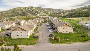 Zona residencial com casas, um estacionamento e uma estrada que leva a uma paisagem montanhosa.