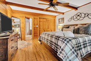 A bedroom with a wooden ceiling fan, a bed with a plaid bedspread, a wooden dresser, and a television on the dresser. - Ellijay Walnut Mountain Cabin - Hot Tub, Fire Table, Pet Friendly and Views (Ellijay)