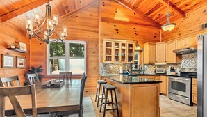 A wooden interior with a dining area, kitchen, and bar. - Ellijay Walnut Mountain Cabin - Hot Tub, Fire Table, Pet Friendly and Views (Ellijay)