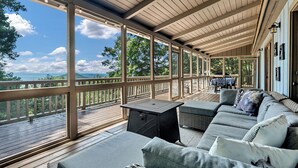 A covered outdoor seating area with a view of the landscape, a table with chairs, and a sofa with cushions. - Ellijay Walnut Mountain Cabin - Hot Tub, Fire Table, Pet Friendly and Views (Ellijay)