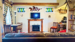 Ein gemütliches Wohnzimmer mit Kamin, Fernseher und Bücherregal.