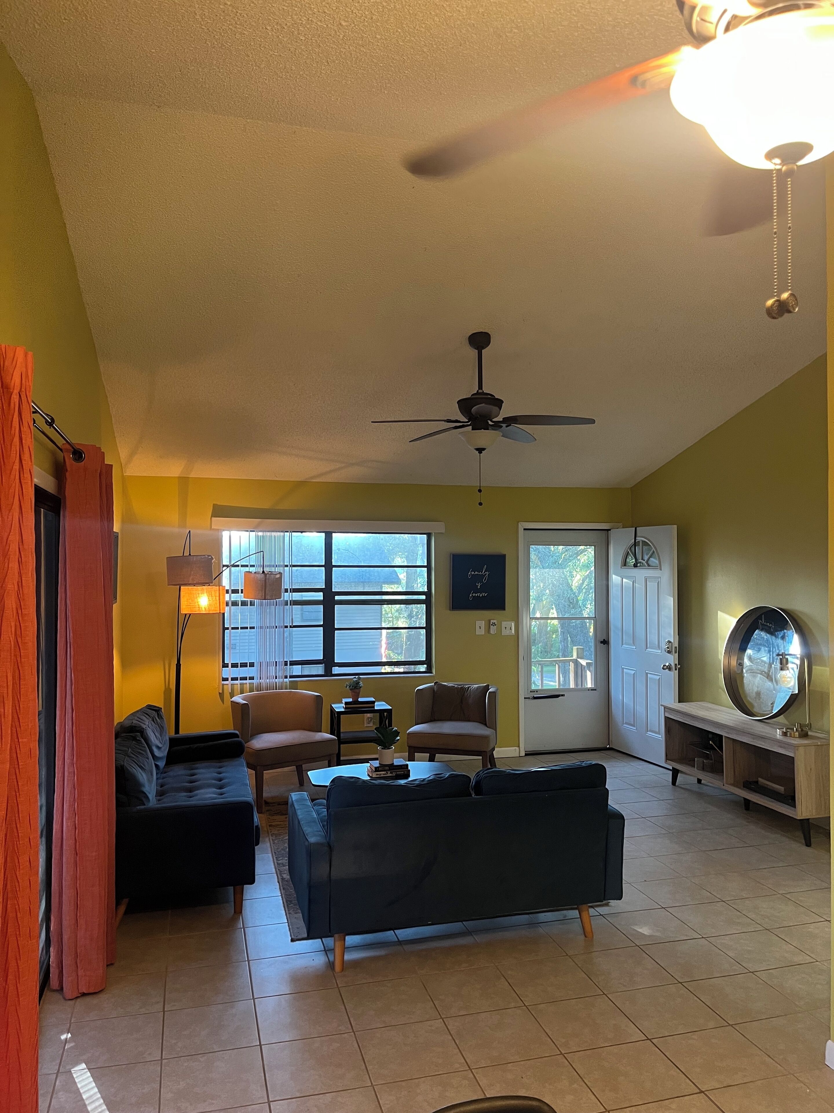 A living room with a ceiling fan, a sofa, a coffee table, and a TV stand.