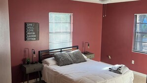 Een slaapkamer met een bed, twee nachtkastjes, een plafondventilator en een motiverende quote op de muur.