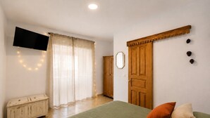A bedroom with a bed, a television, a wardrobe, and a mirror. - CASA DACE Authentic West-Coast Stay (El Albercon)