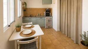 A compact kitchen with a dining table set for two, a microwave, and a small sink. - CASA DACE Authentic West-Coast Stay (El Albercon)