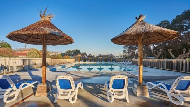 A pool area with lounge chairs and thatched umbrellas. - Hotel Erromardie Plage by Odalys (Saint-Jean-de-Luz)