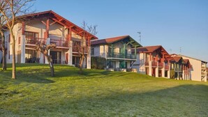 A row of two-story buildings with balconies, a grassy area in front, and a clear sky. - Hotel Erromardie Plage by Odalys (Saint-Jean-de-Luz)