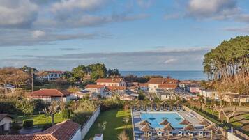 Uma área residencial com piscina, espreguiçadeiras e guarda-sóis.