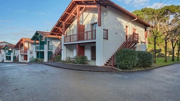 A row of two-story buildings with balconies, a paved driveway, and a clear sky.