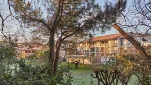 A modern building with a glass facade, surrounded by a well-maintained garden with various trees and shrubs. - Hotel Erromardie Plage by Odalys (Saint-Jean-de-Luz)