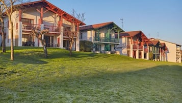 A hotel with multiple buildings, balconies, and a grassy area.
