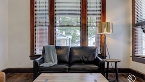 A living room with a black leather sofa, a wooden coffee table, and a floor lamp.
