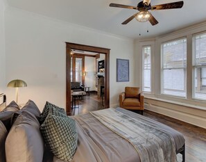 A spacious bedroom with a large bed, a ceiling fan, and a view of the outside through large windows. - Spacious 3-in-1 Vintage Brick Escape (Memphis)