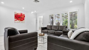 A modern living room with a sectional sofa, a glass coffee table, and a large window with blinds. - Siena Villas in Pompano Beach (Pompano Beach)
