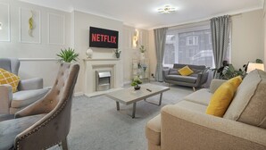 A living room with a fireplace, sofas, a coffee table, and a TV mounted on the wall.