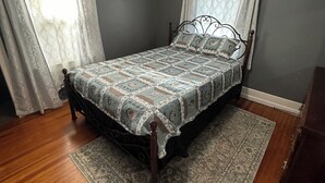 A bedroom with a bed, wooden floor, and a ceiling light fixture. - 3-bedroom Beach House in Beautiful Charlotte near Beach with AC/Heat and Wi-Fi (Rochester)