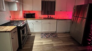 A modern kitchen with white cabinets, a stainless steel refrigerator, and a herringbone-patterned backsplash. - 3-bedroom Beach House in Beautiful Charlotte near Beach with AC/Heat and Wi-Fi (Rochester)