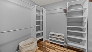 A walk-in closet with open shelving, a hanging rod, and a basket on the floor. - Asheville NC Cottage~Close to shopping and dining~ (Asheville)