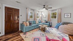 A living room with a sectional sofa, a round coffee table, a fluffy rug, and a ceiling fan. - Asheville NC Cottage~Close to shopping and dining~ (Asheville)