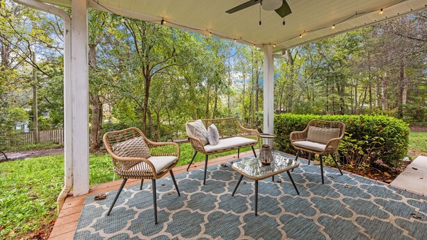 A covered patio with wicker furniture, a ceiling fan, and string lights. - Asheville NC Cottage~Close to shopping and dining~ (Asheville)