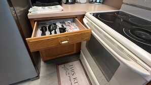 Eine Küche mit Curtis Stone Backofen, einem Mixer, einer Kaffeemaschine und einer Schublade mit Besteck.