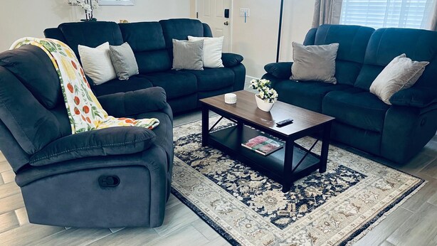 Ein Wohnzimmer mit zwei dunkelblauen Sofas, einem Couchtisch und einem gemusterten Teppich.