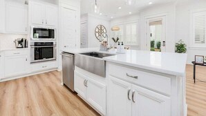 Une cuisine moderne avec des meubles blancs, des appareils en acier inoxydable et un grand îlot central.