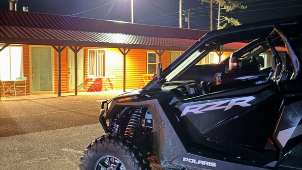A Polaris ATV parked in front of a building with a metal roof and a porch. - Peninsula Point Lodge (Rapid River)
