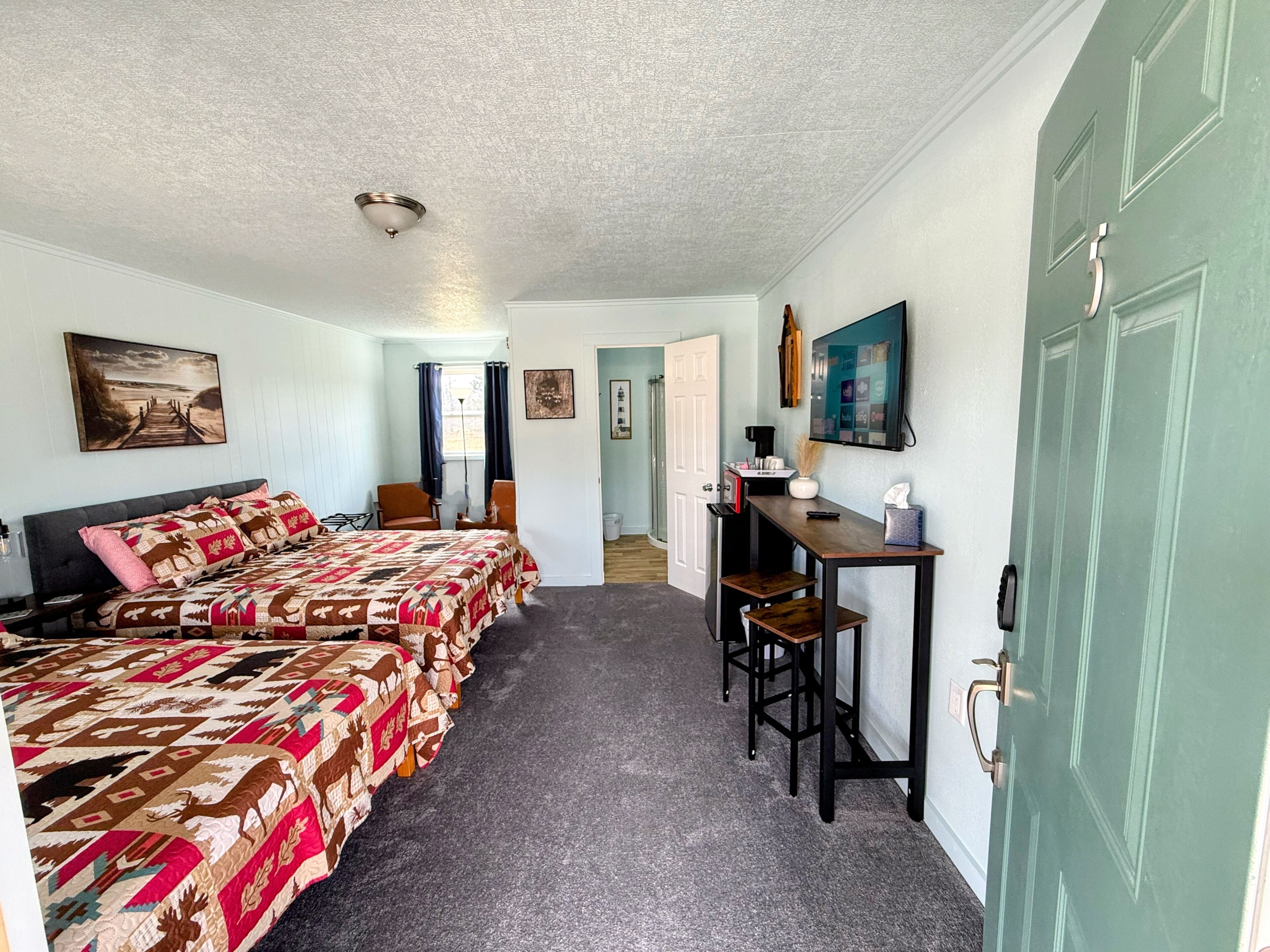 A bedroom with two beds, a desk, and a chair.