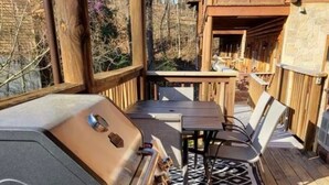 An outdoor deck with a built-in grill, a table with chairs, and a patterned rug.