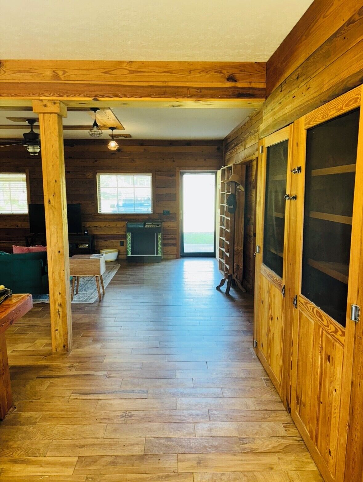 A spacious room with wooden floors and walls, a large sliding door, and a fireplace.