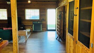 A spacious room with wooden floors and walls, a large sliding door, and a fireplace.