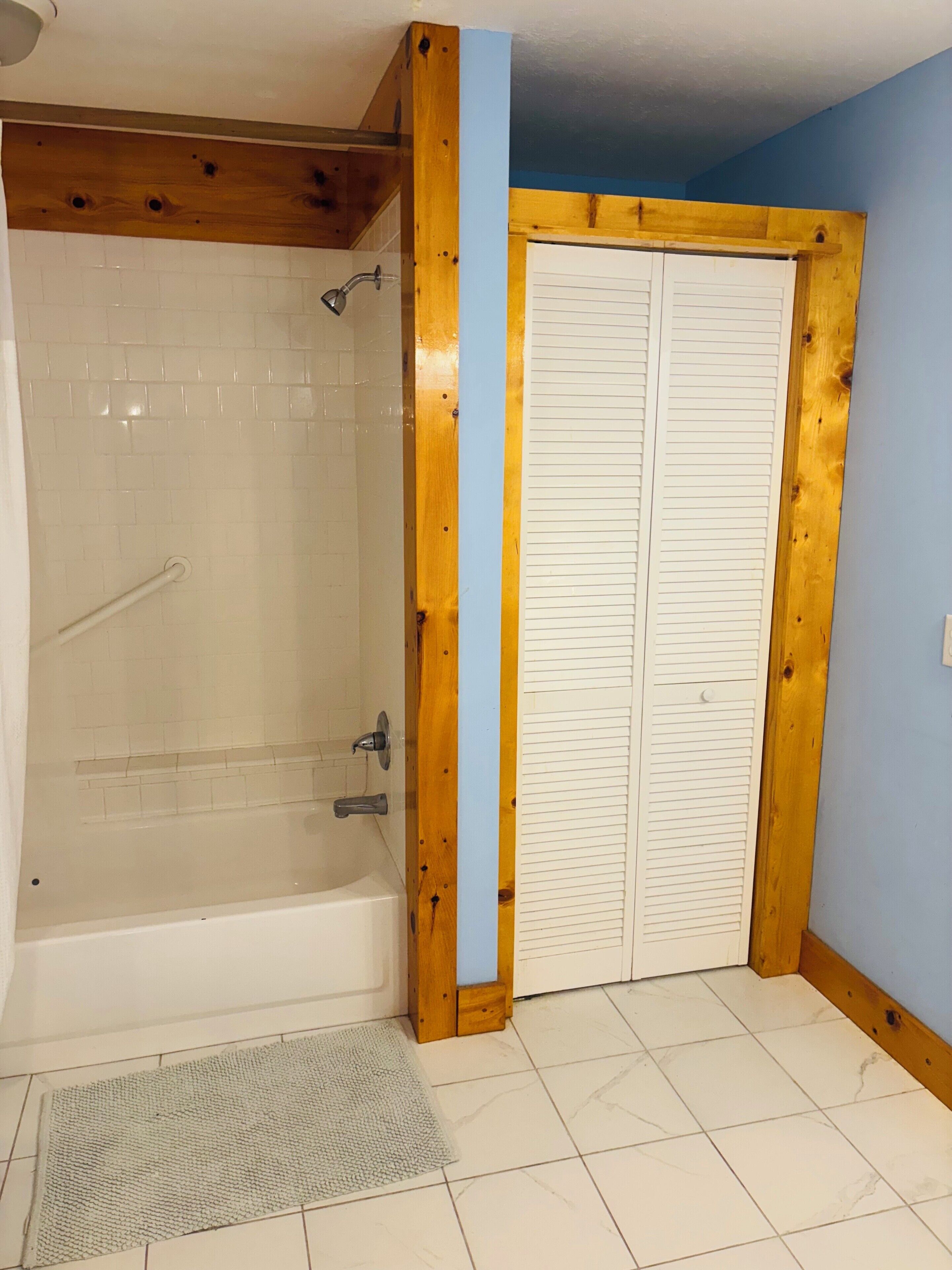 Un baño con bañera, ducha y puerta de madera.
