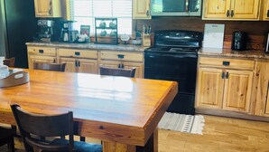A kitchen with wooden cabinets, a black stove, a microwave, and a coffee maker. - Lake front Farm Cabin, Hot Tub, Star Gazing with Telescope, Fire pit (Kite)