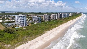 Un hotel costero con varios edificios altos, acceso directo a la playa y vistas al océano.