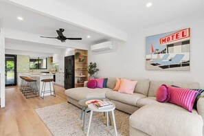 A modern living room with a sofa, a coffee table, and a bar area with stools.