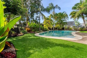 A swimming pool surrounded by well-maintained grass and tropical plants. - The Noosa Villa Luxe Townhouse in Great Location (Noosa)