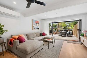 Ein modernes Wohnzimmer mit einer Couch, einem Couchtisch und einem Essbereich mit Stühlen und einem Tisch.