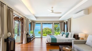 Een ruime slaapkamer met een groot bed, een bank en uitzicht op zee.