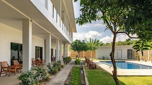 Un edificio moderno con un área de estar al aire libre cubierta, piscina y un jardín bien cuidado.