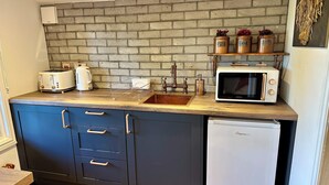 A compact kitchen with a brick backsplash, a sink, a microwave, and a refrigerator. - Rustic Roost: Countryside, Warm Cabin w/ Countryside Views & King Bed (Maybole)