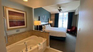 A hotel room with a large bathtub, a bed, a desk, and a chair. - Club Wyndham National Harbor (Oxon Hill)